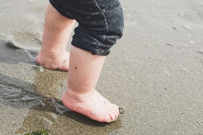 Low section of man standing on sand