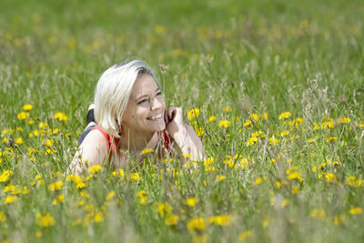 Woman lying in yellow flowers growing in field