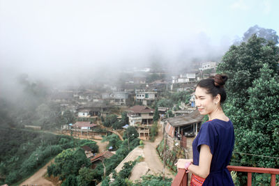 Woman standing at observation point during foggy weather