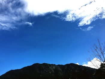 Low angle view of silhouette mountains against blue sky