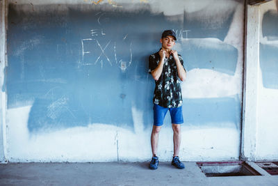 Portrait of young man standing against weathered wall