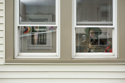 View of musician at window singing with guitar into microphone