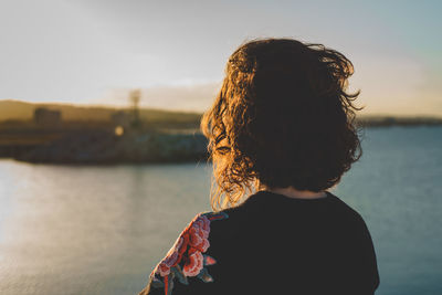 Rear view of girl looking at sea against sky