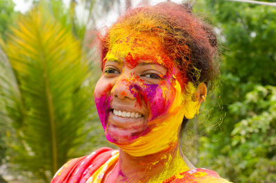 Young indian happy woman with color on face on holi color festival. front view. looking at camera.