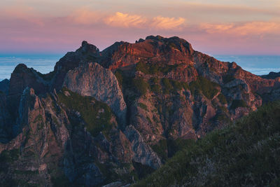 Rock formations by sea against sky during sunset