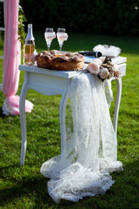 Cake with champagne on table in field