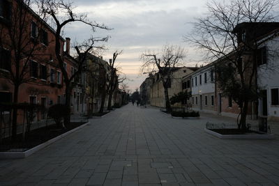 Footpath amidst buildings in city against sky