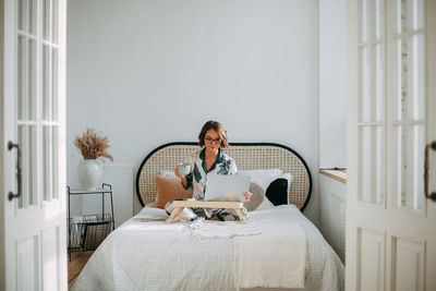 Young girl sitting on bed with laptop