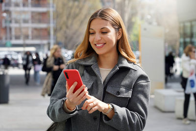 Smiling woman using mobile phone in city