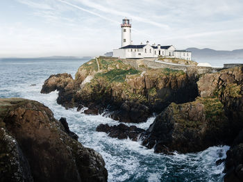 Lighthouse by sea against sky