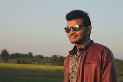 Portrait of young man wearing sunglasses standing on field