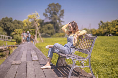 Woman sitting on seat against sky
