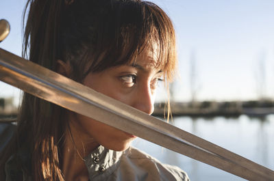 Female athlete with intense look holding sword against her face on sunny day