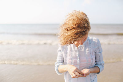 Young woman collecting seashells on beach