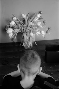 Portrait of boy with flower vase on table at home