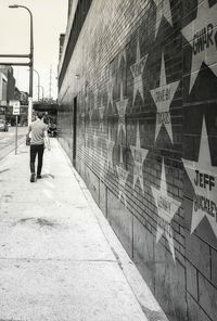 Rear view of man walking on footpath