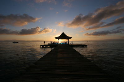 Silhouette pier over sea against sky during sunset