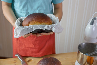 Midsection of woman holding bread in kitchen