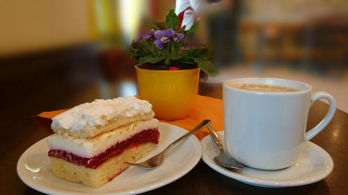 Cake by coffee cup in plate on table