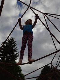 Low angle view of girl standing on rope against sky