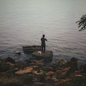 Rear view of man fishing in sea