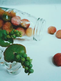 High angle view of yumberry and jars on white table