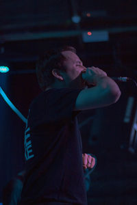 Side view of young man standing at music concert