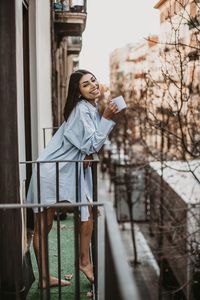 Portrait of young woman standing against railing