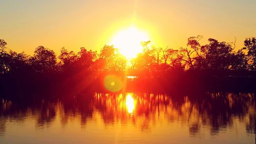 Silhouette trees by lake against sky during sunset