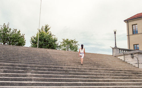 Rear view of woman on staircase against sky
