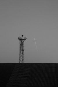 Low angle view of silhouette communications tower against sky