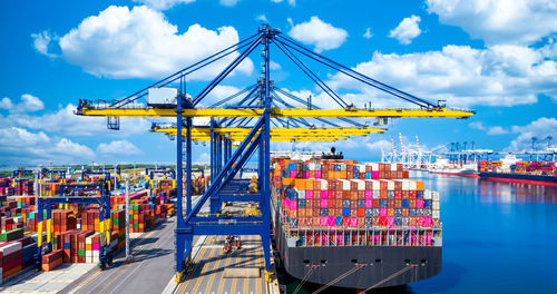 Cranes at commercial dock against sky