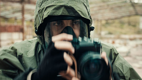 Military man with gas mask and camera photographs the destruction of the bomb