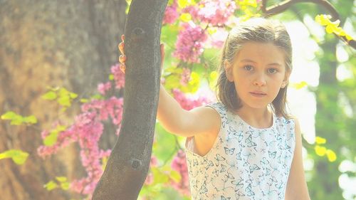 Portrait of happy girl standing by tree in park