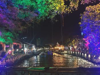 Illuminated bridge over river in city at night