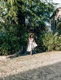 Woman standing by tree against plants