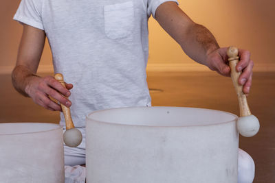 Midsection of man playing singing bowl at spa