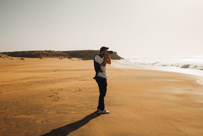 Man photographing at beach against sky