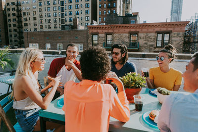 Happy friends enjoying snacks while talking on terrace