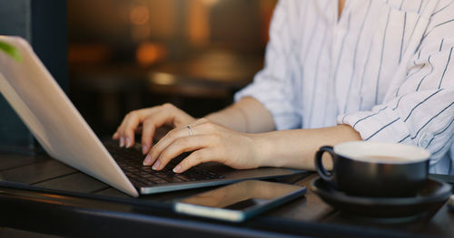 Midsection of woman using laptop at table