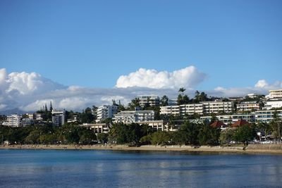 View of townscape by sea against blue sky