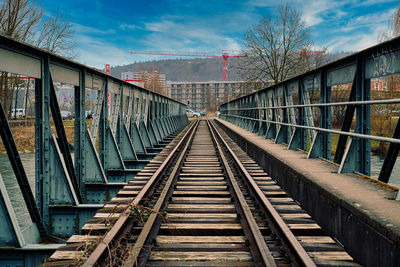 Footbridge over railroad tracks against sky