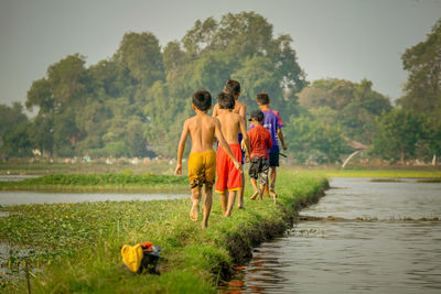 Rear view of kids standing in lake