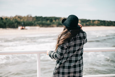 Rear view of woman standing against sea