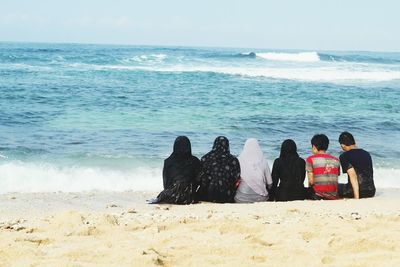 Rear view of people sitting at beach