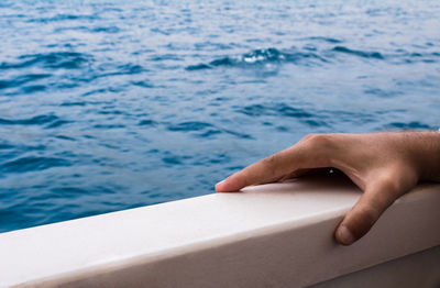 Cropped hand on railing against sea