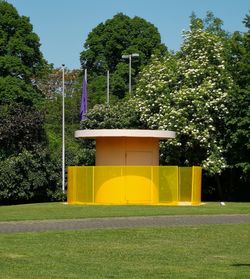 Yellow flowers on building by trees against sky