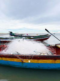 Boat wi th fish net moored in sea against sky