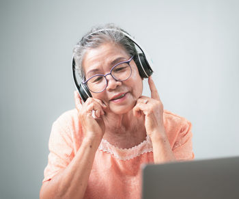 Old senior woman happily using headphones,streaming onlinewatching video on internet, live concert, 