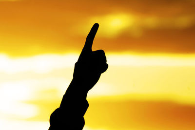 Close-up of silhouette hand against sky during sunset